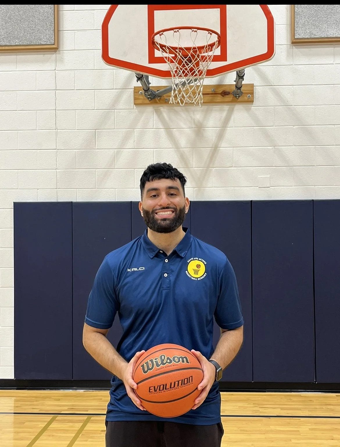 Coach Anthony Gonzales holding a basketball in the gym