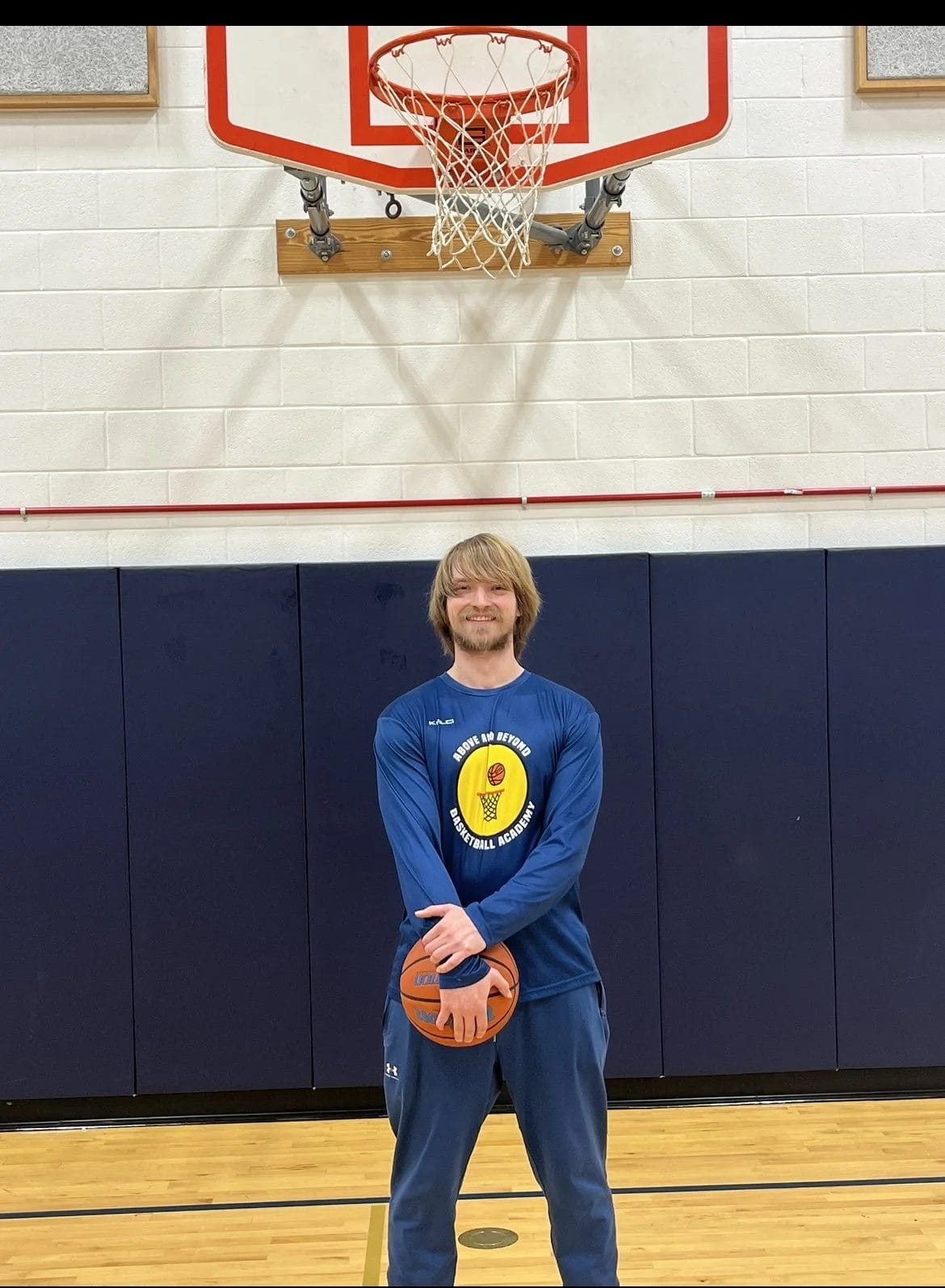 Coach Mike Leybo holding a basketball in the gym